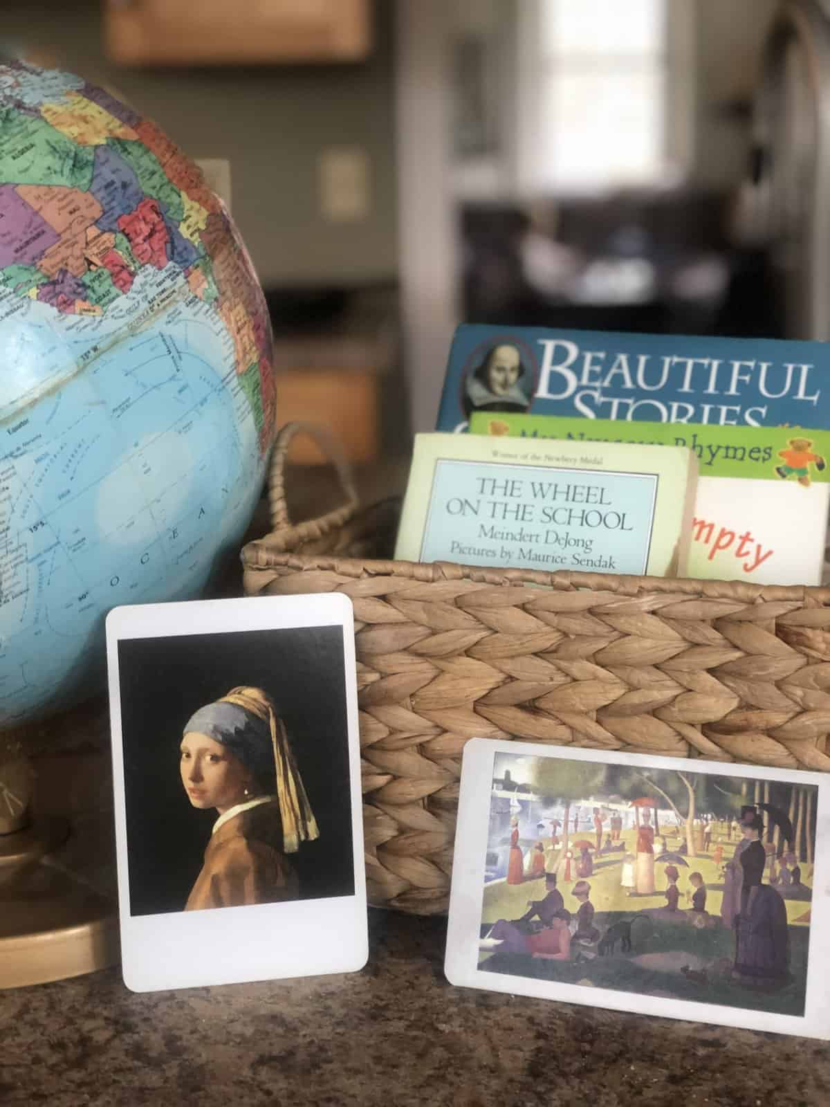 books in a basket next to a globe and art prints